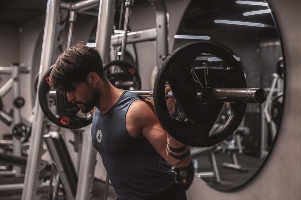 Muscular man lifting weights in a modern gym, focusing on strength training.