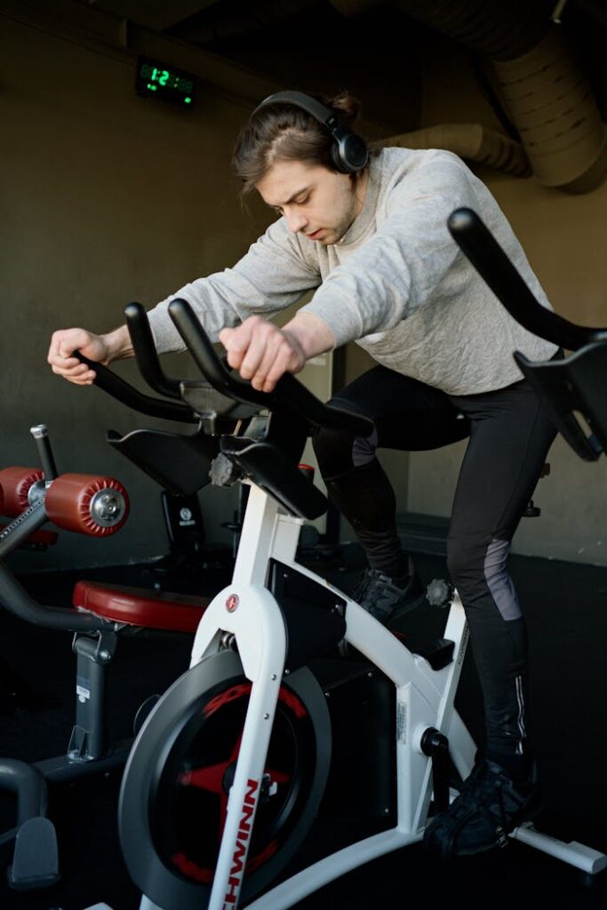 Young man focused on workout using exercise bike in gym
