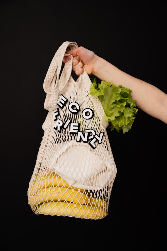 The Art of Drawing Readers In: Your attractive post title goes here Hand holding eco-friendly string bag with bananas and lettuce on black background.